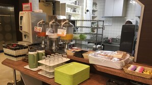Una barra de desayuno con diversas opciones de comida y bebidas, como café, té y pasteles.