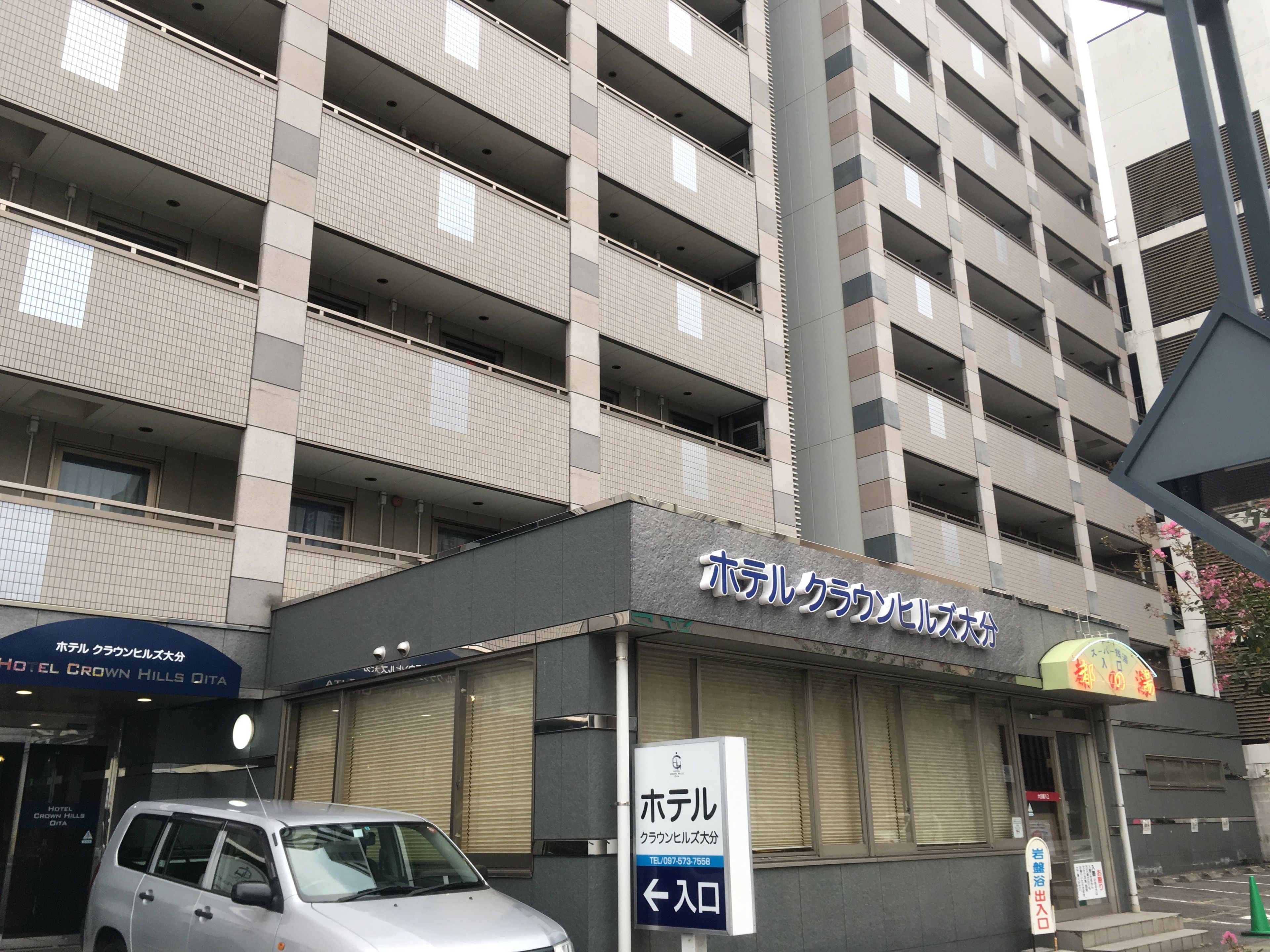 A multi-story building with a sign for Hotel Crown Hills Qita.