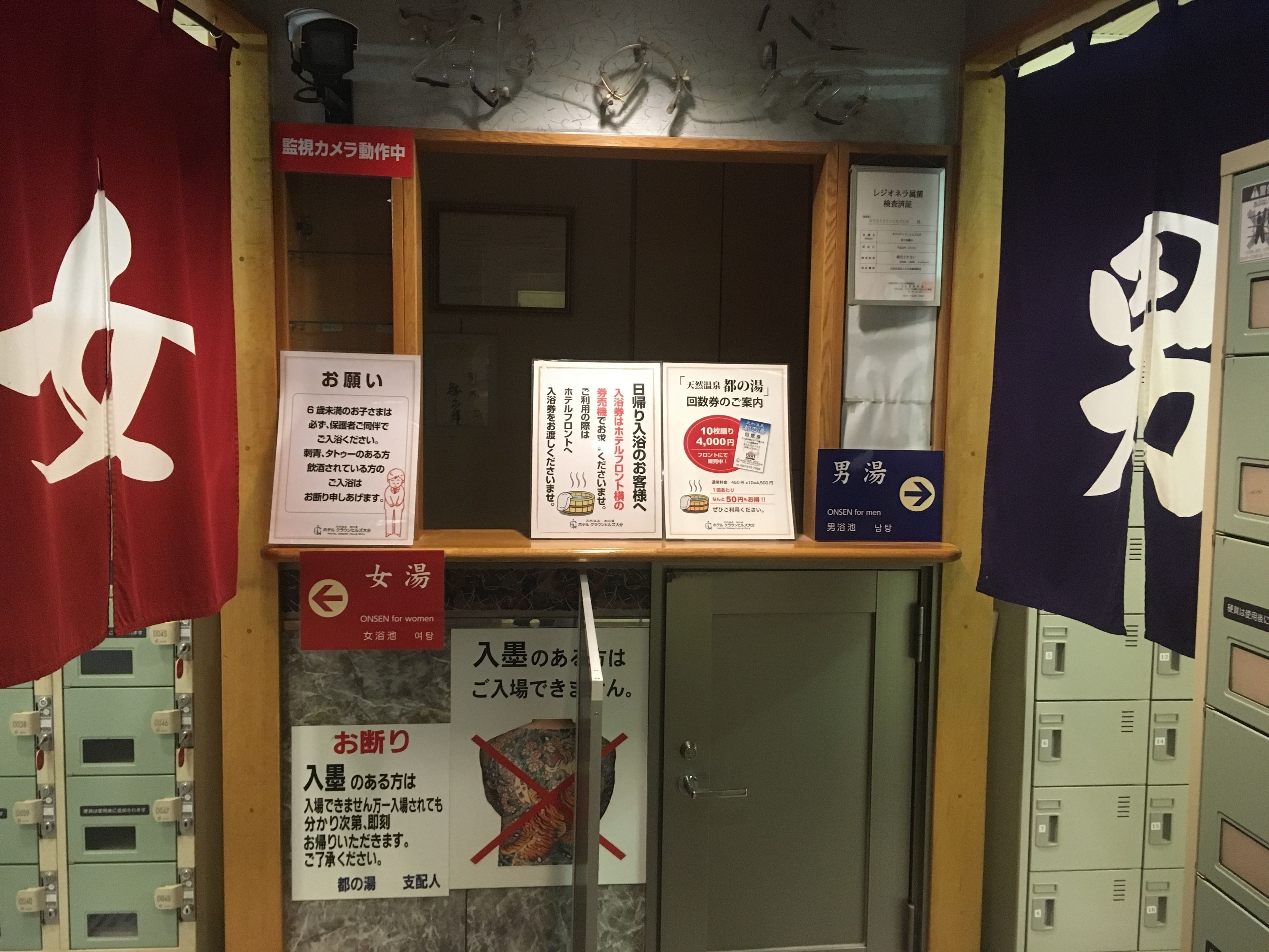 A room with a wooden door, a red and white sign, and a blue sign with white text.