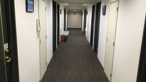 Un pasillo de hotel con varias puertas, un extintor y un banco.