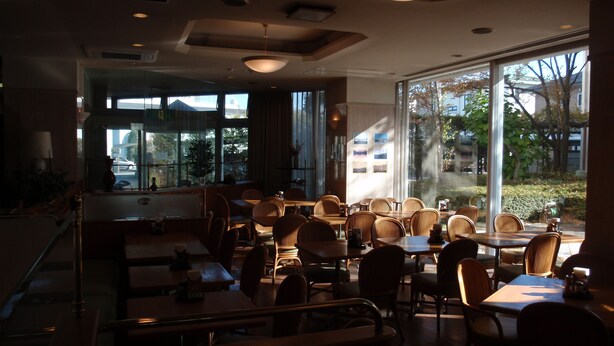A restaurant with multiple tables and chairs, large windows, and a modern interior design. - Hotel Crown Hills Okaya (Okaya)