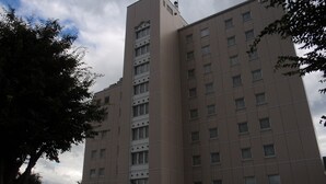 A multi-story building with a modern architectural design, featuring a central vertical element and a uniform facade. - Hotel Crown Hills Okaya (Okaya)