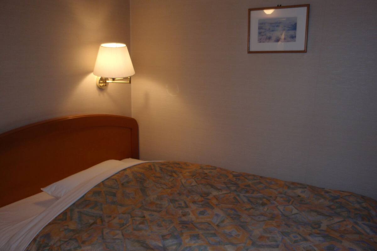 Ein Hotelzimmer mit einem Bett, einer Wandlampe und einem gerahmten Bild an der Wand.