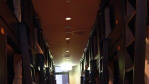 A hallway with wooden flooring and bookshelves on both sides. - Resort Capsule Sakuragicho (Yokohama)