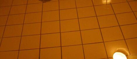 A tiled hot tub with a drain and a light fixture above it.