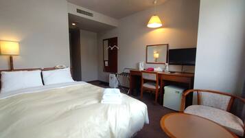 A hotel room with a bed, desk, chair, and a television.