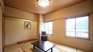 A traditional Japanese room with tatami flooring, a low table, a television, and large windows. - Hotel Crown Hills Takefu (Echizen)