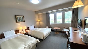 A hotel room with two beds, a desk, a chair, a TV, and a window with a view.