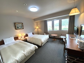 A hotel room with two beds, a desk, a chair, a TV, and a window with a view. - Hotel Crown Hills Takefu (Echizen)
