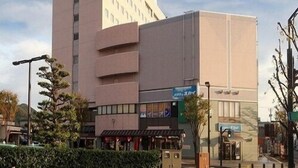 A modern hotel with a prominent corner building, a ground-level restaurant, and a clear sky. - Hotel Crown Hills Takefu (Echizen)