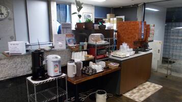 A reception area with a coffee machine, a clock, and a welcome drink sign.