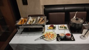 Una mesa de buffet con distintos alimentos y utensilios.