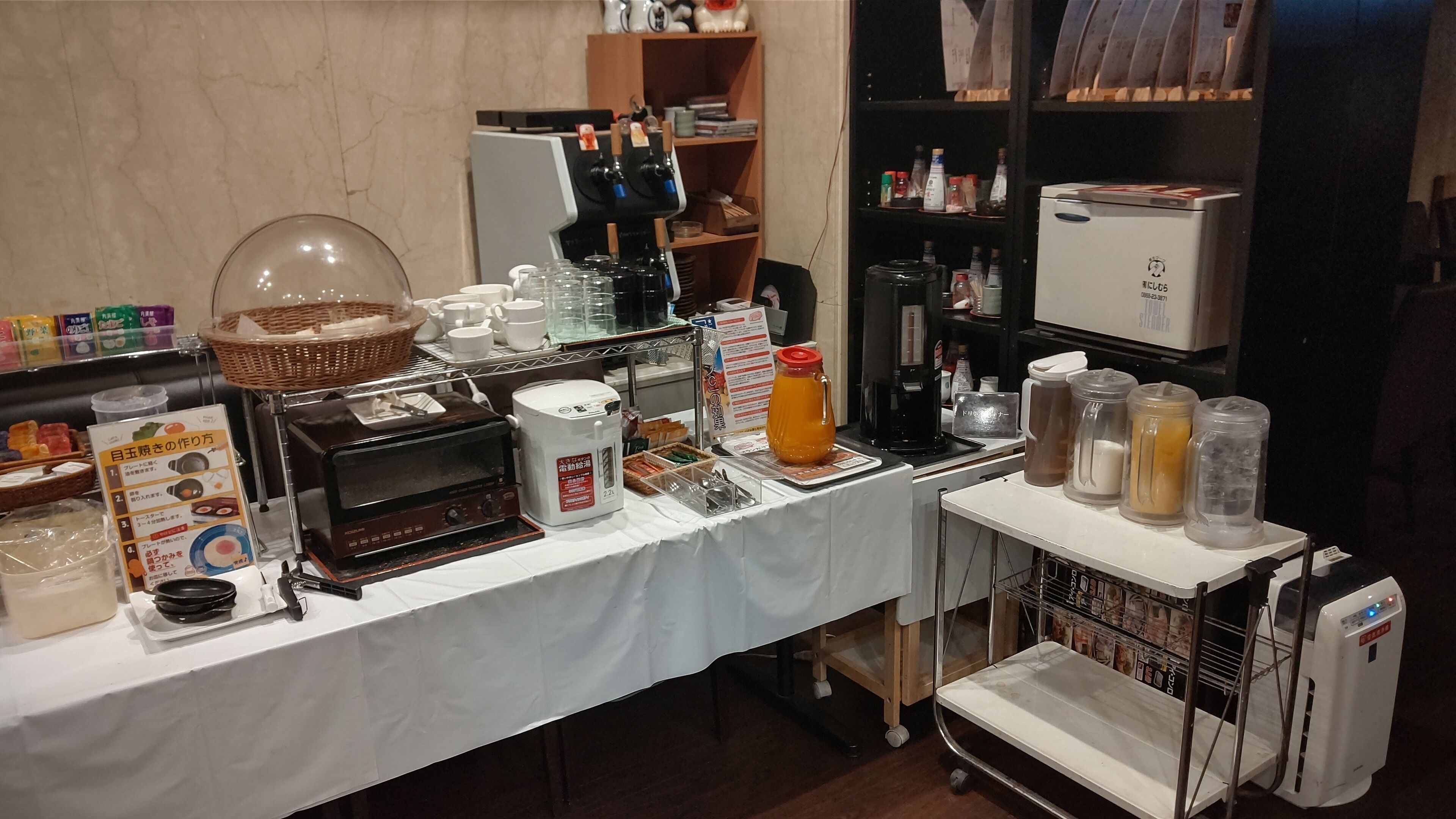 A buffet setup with a coffee machine, a beverage dispenser, and various food items on a table.