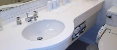 A modern bathroom with a white sink, a mirror, a toilet, and a shower area.