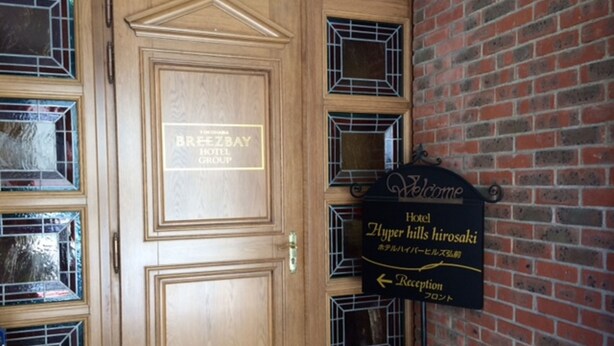 A hotel entrance with a reception sign and a wooden door with a plaque. - Hotel Hyper Hills Hirosaki (Hirosaki)
