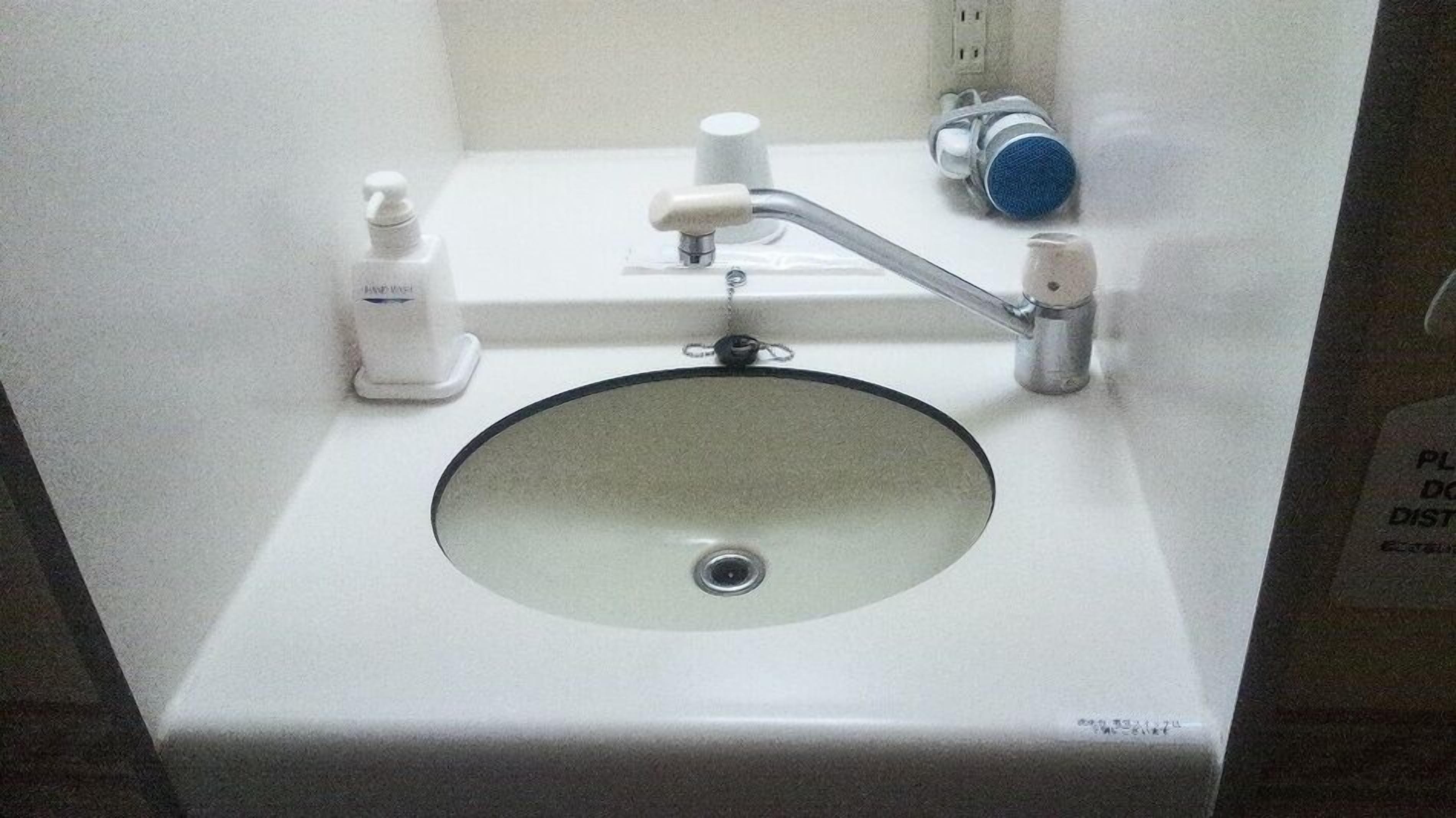 Ein Waschbecken mit Spiegel, Seifenspender und Wasserhahn.