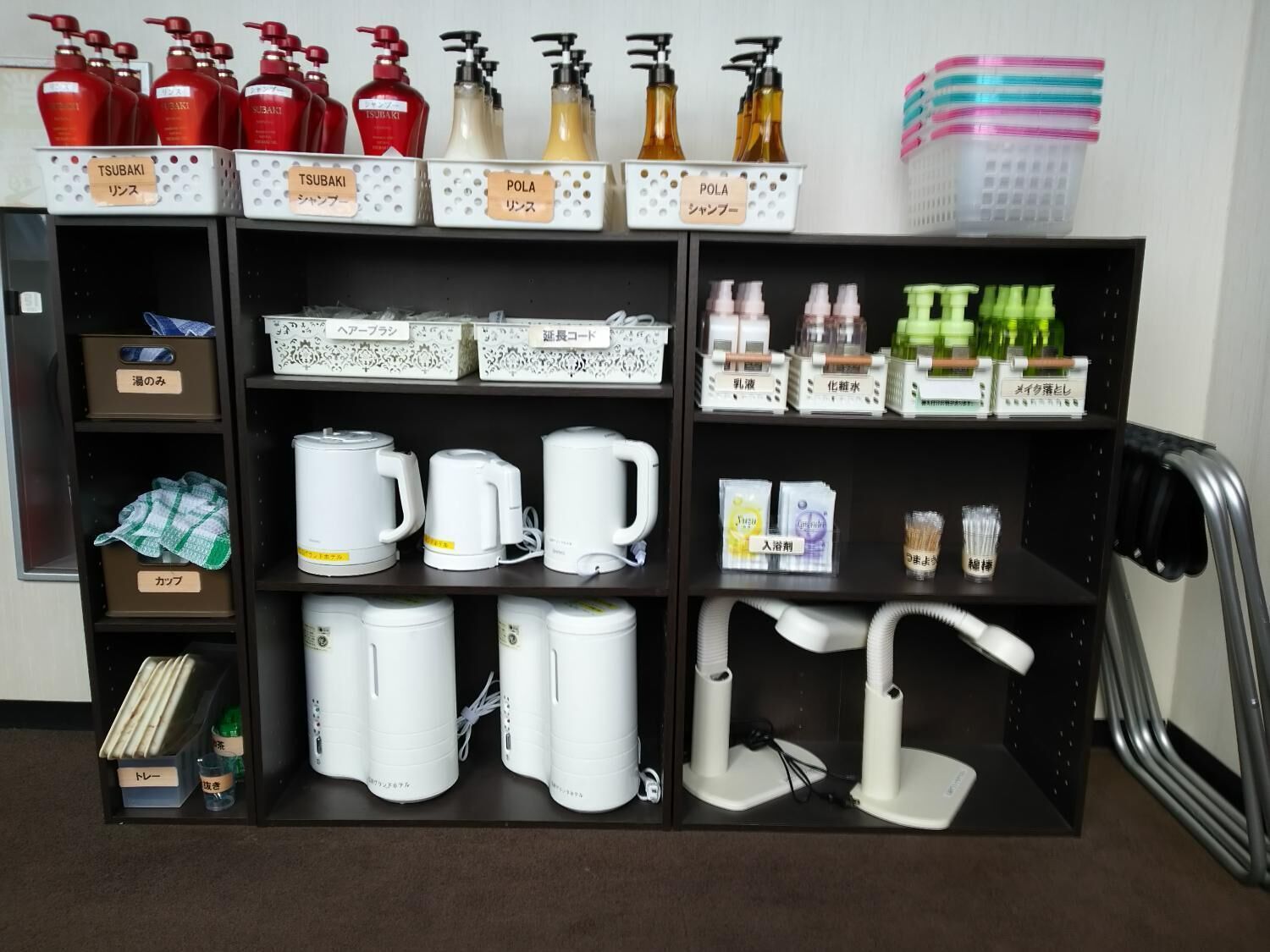A hotel room with a minibar stocked with toiletries, a coffee maker, and a hairdryer.
