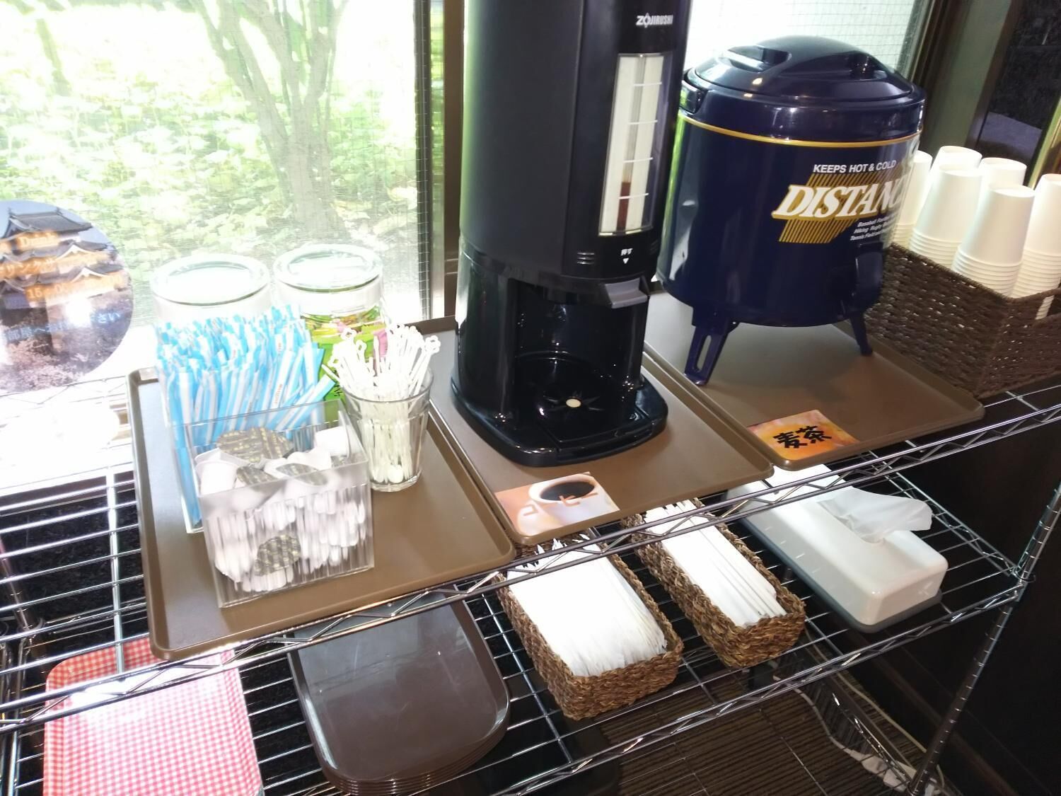 Une machine à café, un distributeur d’eau et des gobelets jetables sur un comptoir.