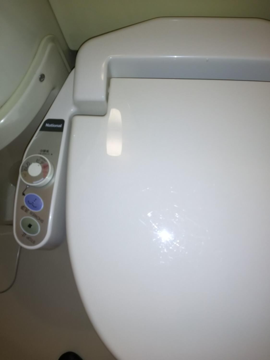 Des toilettes blanches dotées d’un panneau de commande avec des boutons pour la chasse d’eau, la fonction bidet et le réglage de la température de l’eau du bidet.