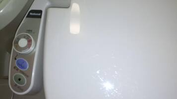 A white toilet with a control panel featuring buttons for flushing, bidet, and bidet water temperature.