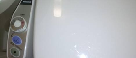 Des toilettes blanches dotées d’un panneau de commande avec des boutons pour la chasse d’eau, la fonction bidet et le réglage de la température de l’eau du bidet.