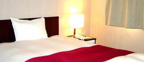 A hotel room with a bed, a nightstand, a lamp, and a framed picture on the wall.