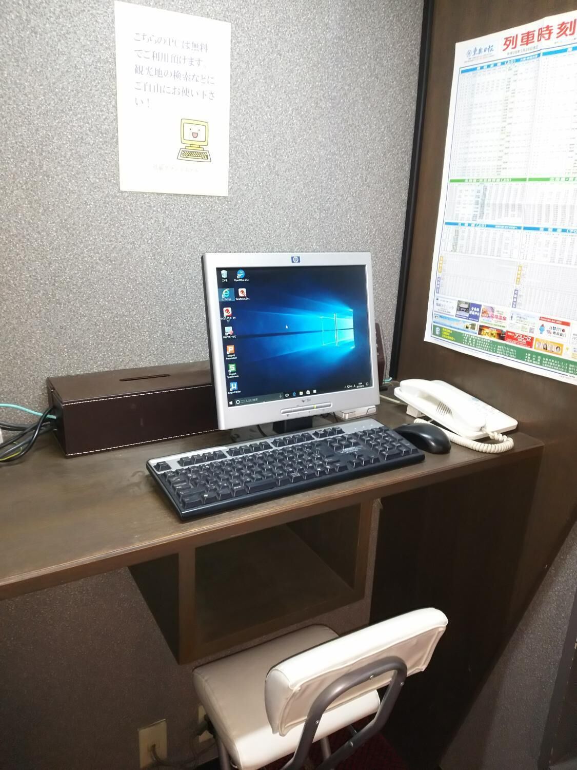 A desk with a computer, keyboard, and phone.