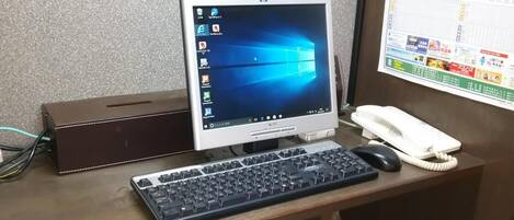 A desk with a computer, keyboard, and phone.