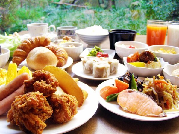 A table with various dishes including fried chicken, pastries, and salads, suggesting a buffet-style meal. - Hirosaki Prince Hotel (Hirosaki)