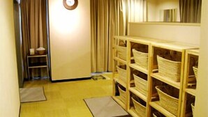 A hallway with wooden shelves filled with baskets, a clock on the wall, and a door with curtains. - Mito Riverside Hotel (Mito)