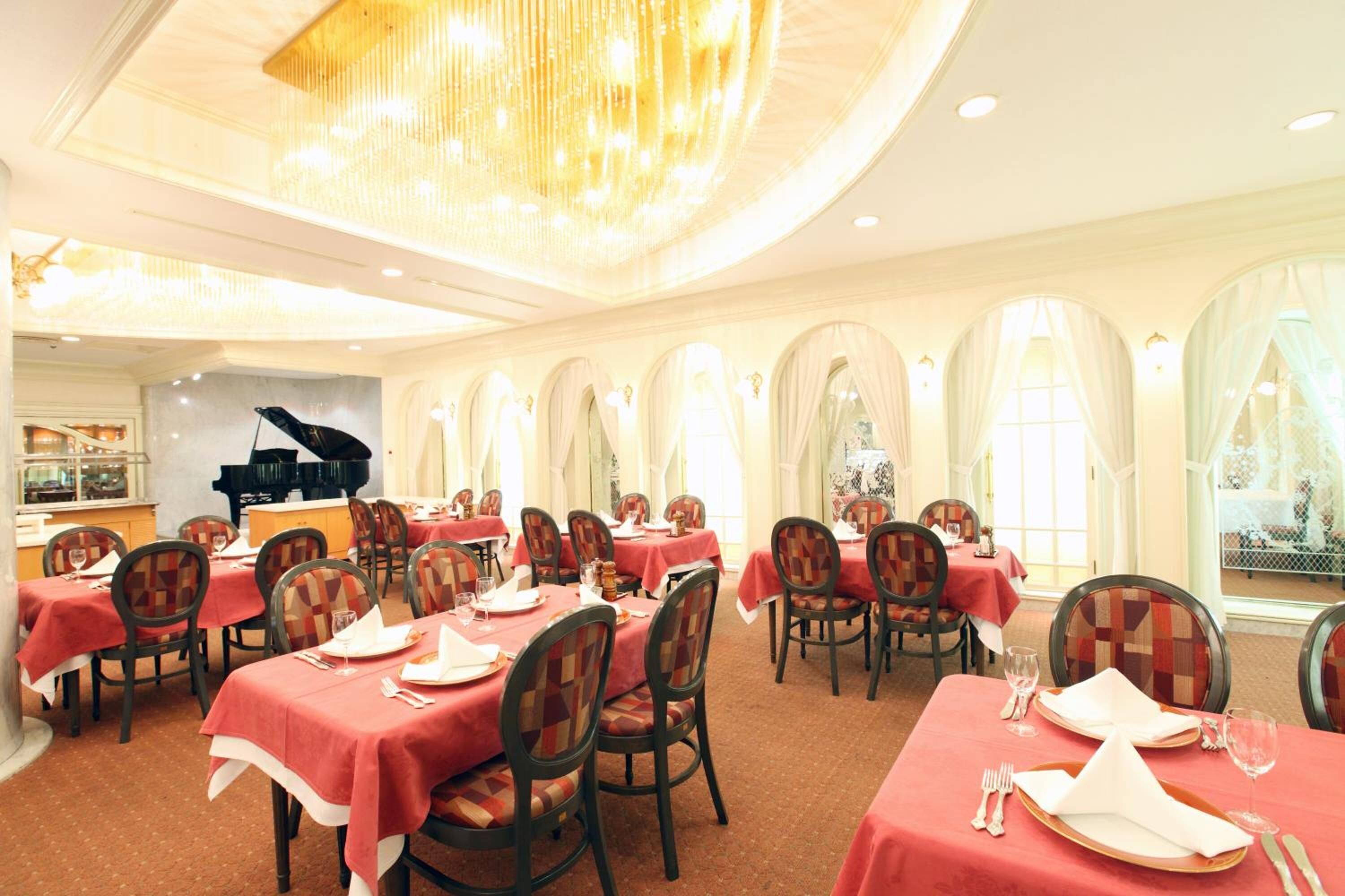A dining area with tables set for four, featuring checkered chairs and red tablecloths.