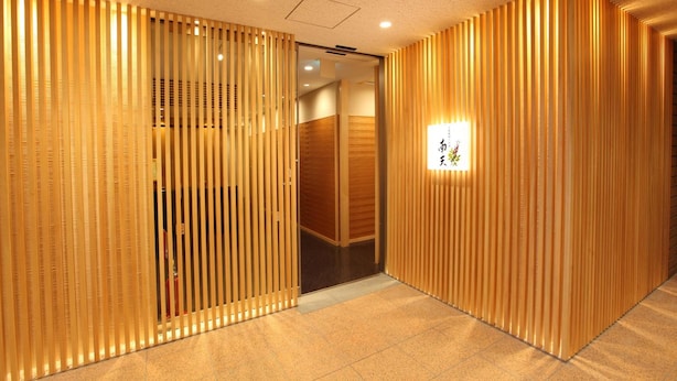 A corridor with vertical wooden slats and a lit sign with Japanese characters. - Nagaoka Grand Hotel (Nagaoka)