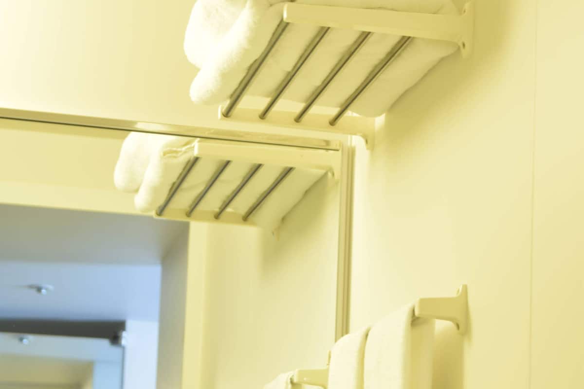 Un baño con toallero y toallas dobladas, además de un espejo.