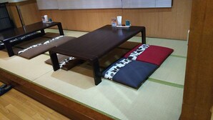 Una habitación con tatamis, una mesa baja y bancos.