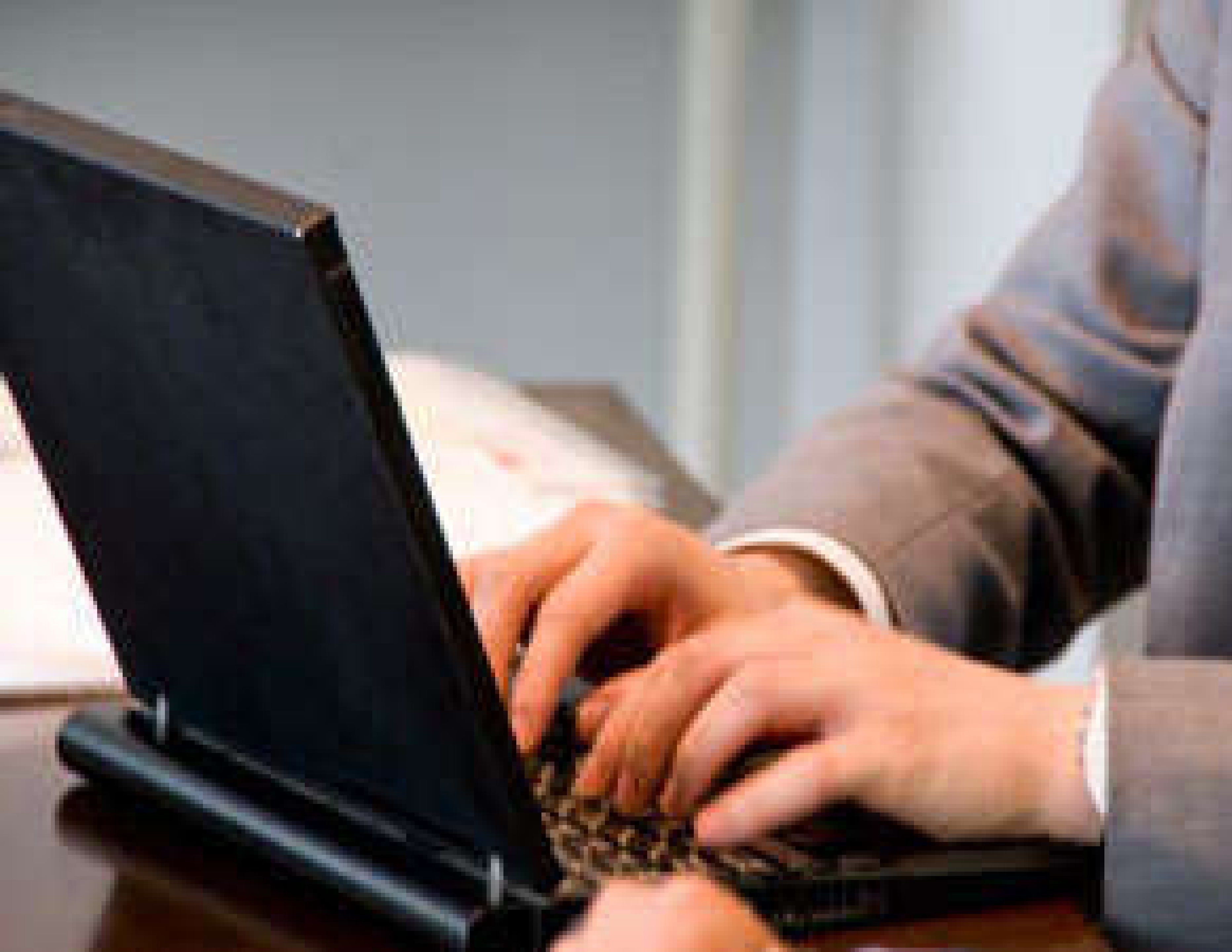 Eine Person benutzt einen Laptop auf einer Holztisch.