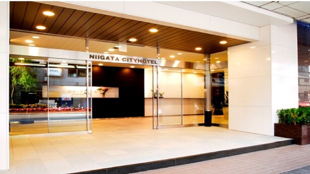 The entrance of Niigata City Hotel with a modern design, glass doors, and a well-lit interior.