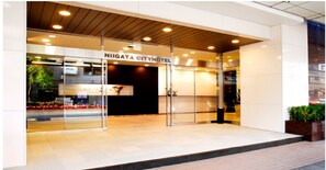 L'entrée de l'hôtel Niigata City, avec son design moderne, ses portes en verre et son intérieur bien éclairé.