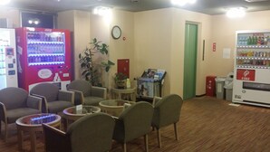 A waiting area with seating, vending machines, a clock, and a fire extinguisher. - Hotel Onahama Hills (Iwaki)