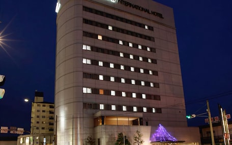 A modern hotel building with a sign reading "Oustat International Hotel".