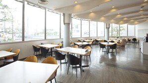A spacious dining area with multiple tables and chairs, large windows offering a view of the city, and a modern ceiling design. - Oustat International Hotel Tajimi (Tajimi)