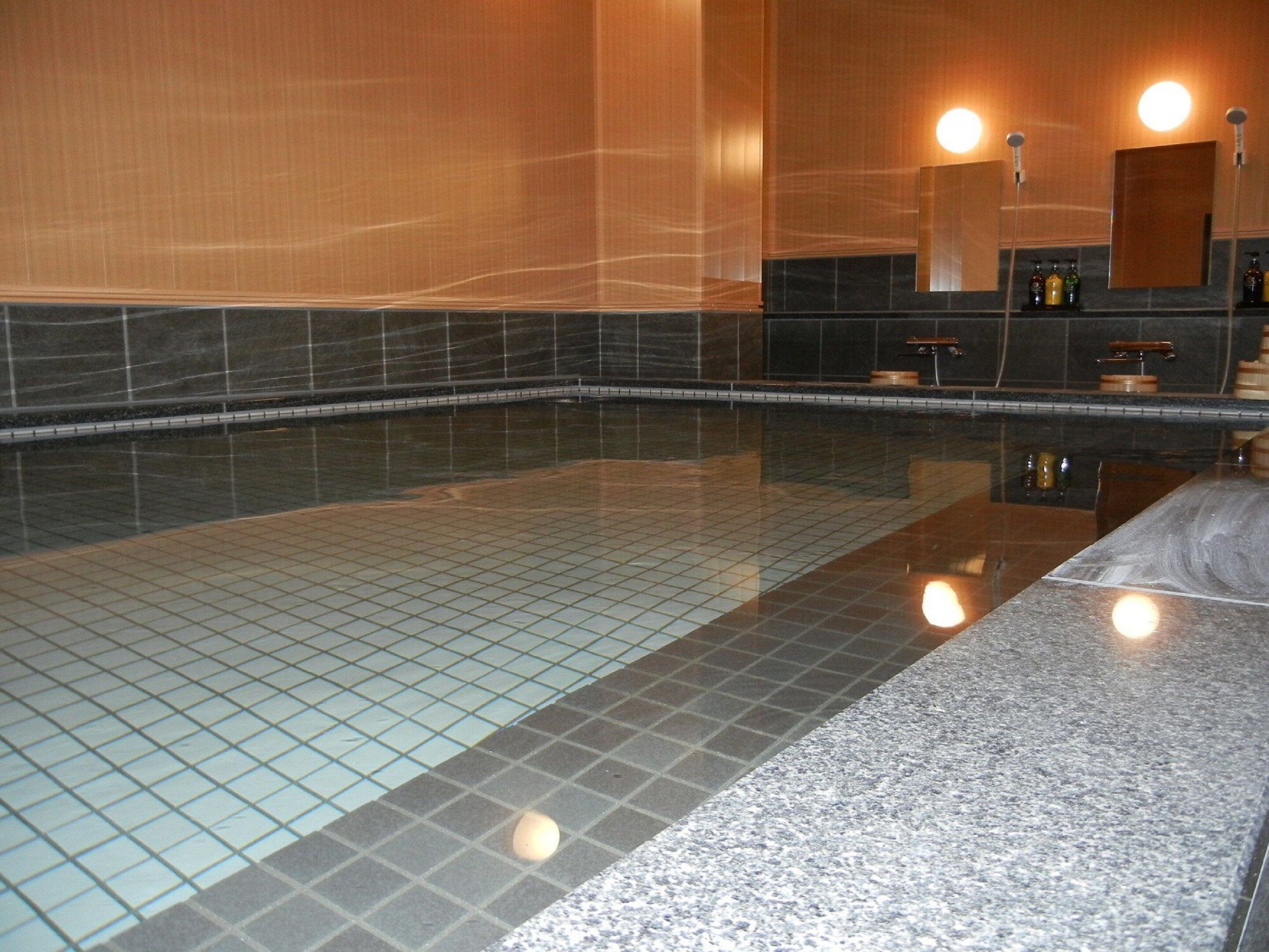 A large indoor swimming pool with tiled walls and a granite floor.