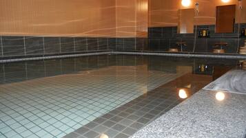 A large indoor swimming pool with tiled walls and a granite floor.