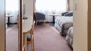 A hotel room with a bed, a desk, a chair, a small table, and a window with curtains. - Oustat International Hotel Tajimi (Tajimi)