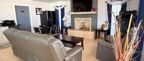 A living room with a sofa, a fireplace, a television, and a dining area.