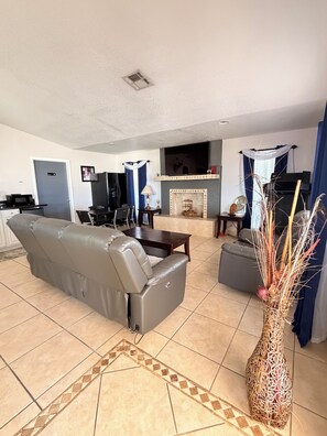 A living room with a sofa, a fireplace, a television, and a dining area.