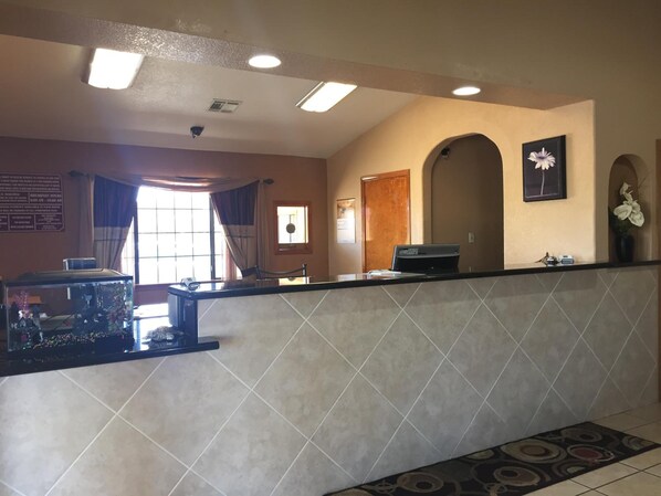 A reception area with a tiled counter, a fish tank, and a window with curtains. - Royal Inn Pearsall (Pearsall)