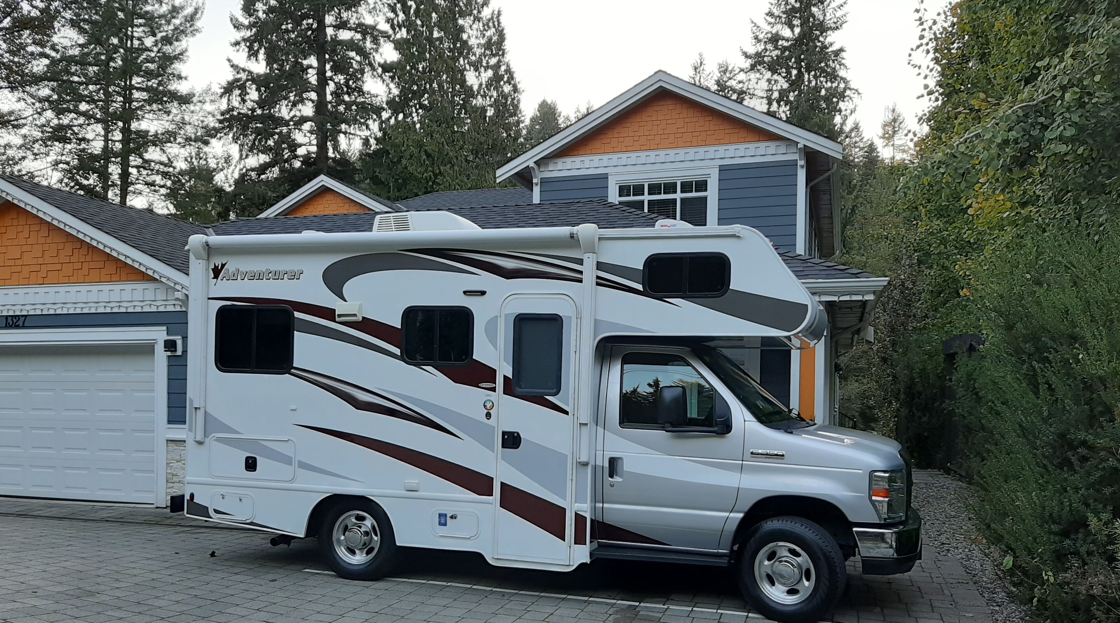 Un grand camping-car était garé devant une maison avec un garage.