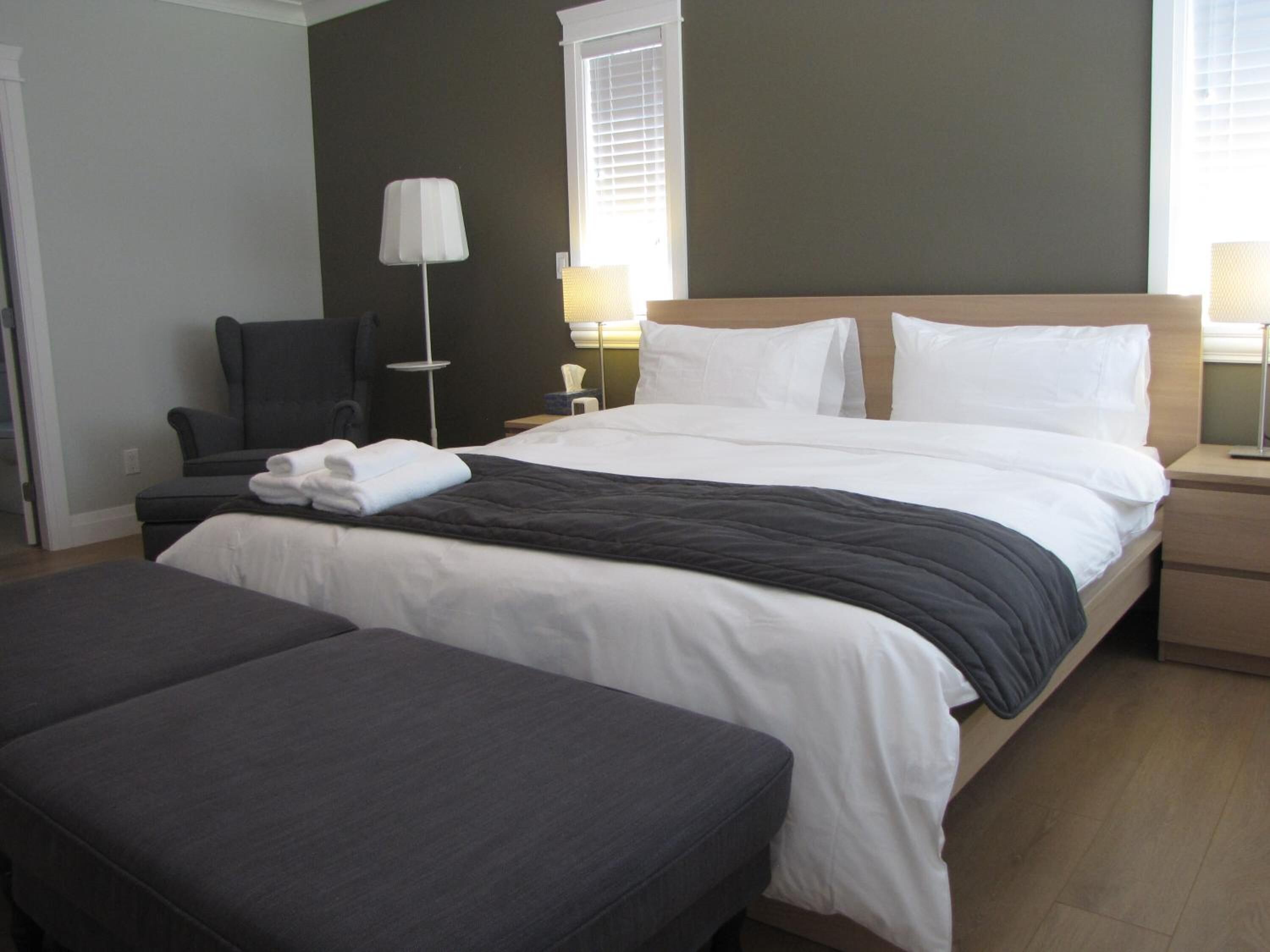 Una habitación de hotel con una cama, una silla, un escritorio y una lámpara.