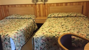 A room with two single beds, each with floral bedding, a wooden headboard, and a nightstand. There are two wall-mounted lamps above the beds. - Black Forest Inn of Adamstown (Adamstown)