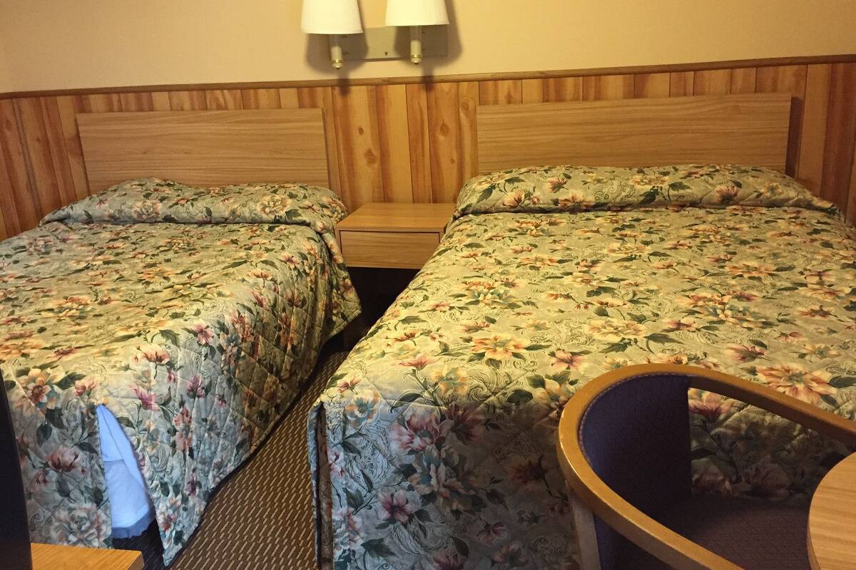 Huoneessa on kaksi erillistä sänkyä, joissa on kummassakin kukallinen vuodevaatesetti, puinen pääty ja yöpöytä. Sänkyjen yläpuolella on kaksi seinään kiinnitettyä lamppua.